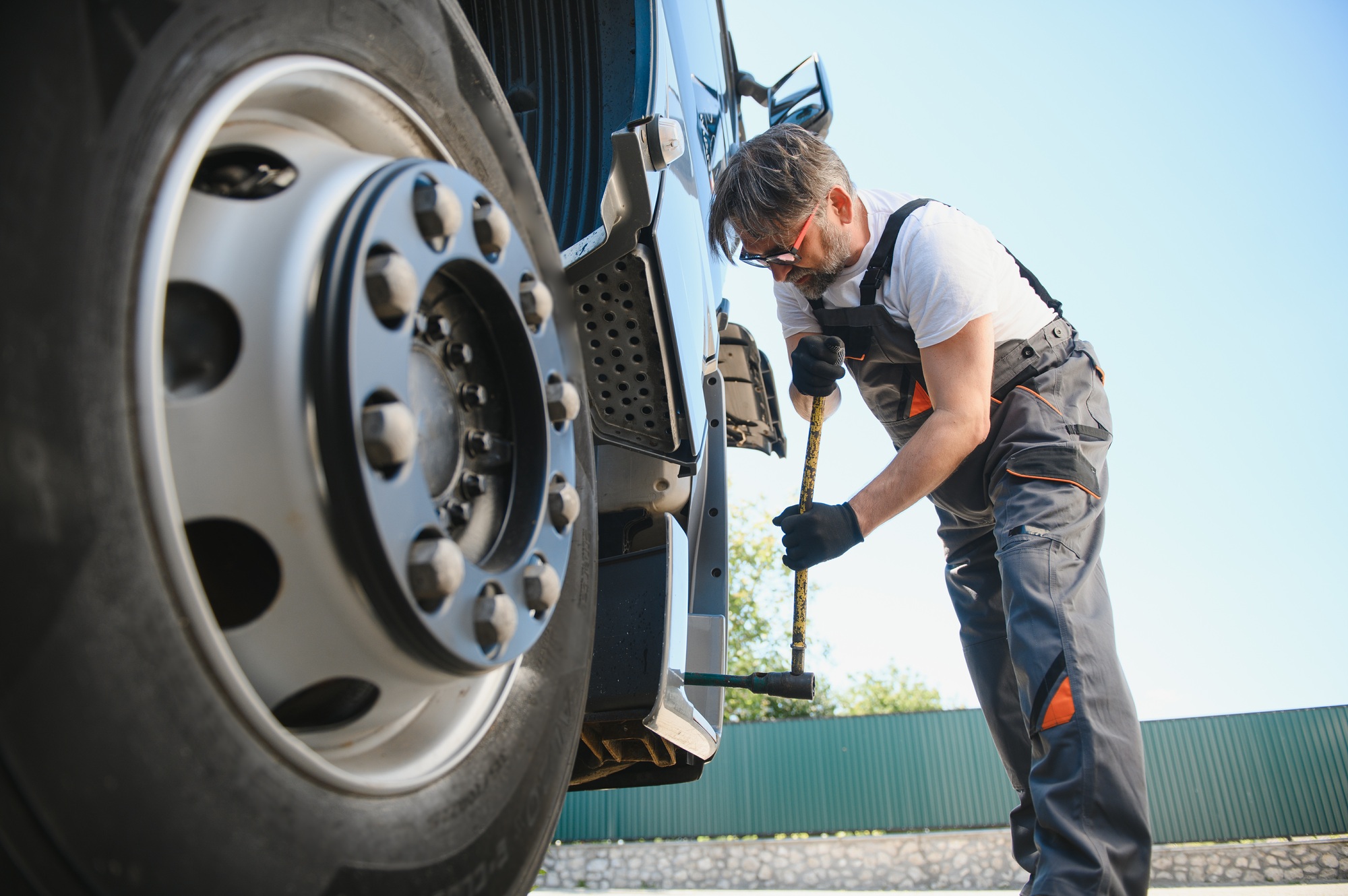 Truck repair service. Mechanic works with tire in truck workshop